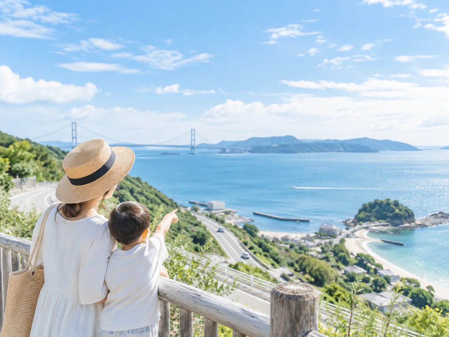 海と橋を見渡す高台で景色を楽しむ親子